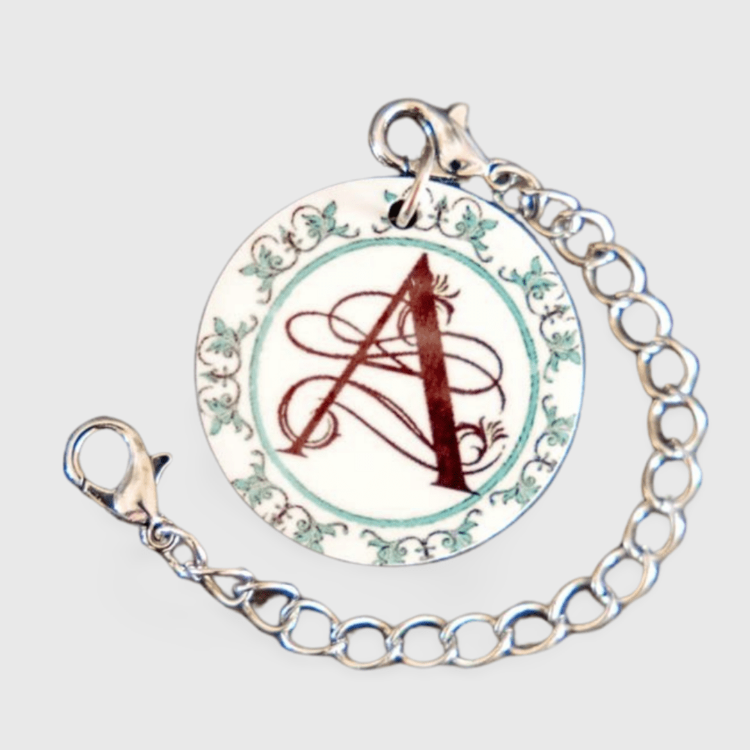 A chain bracelet with a round charm and the letter a.