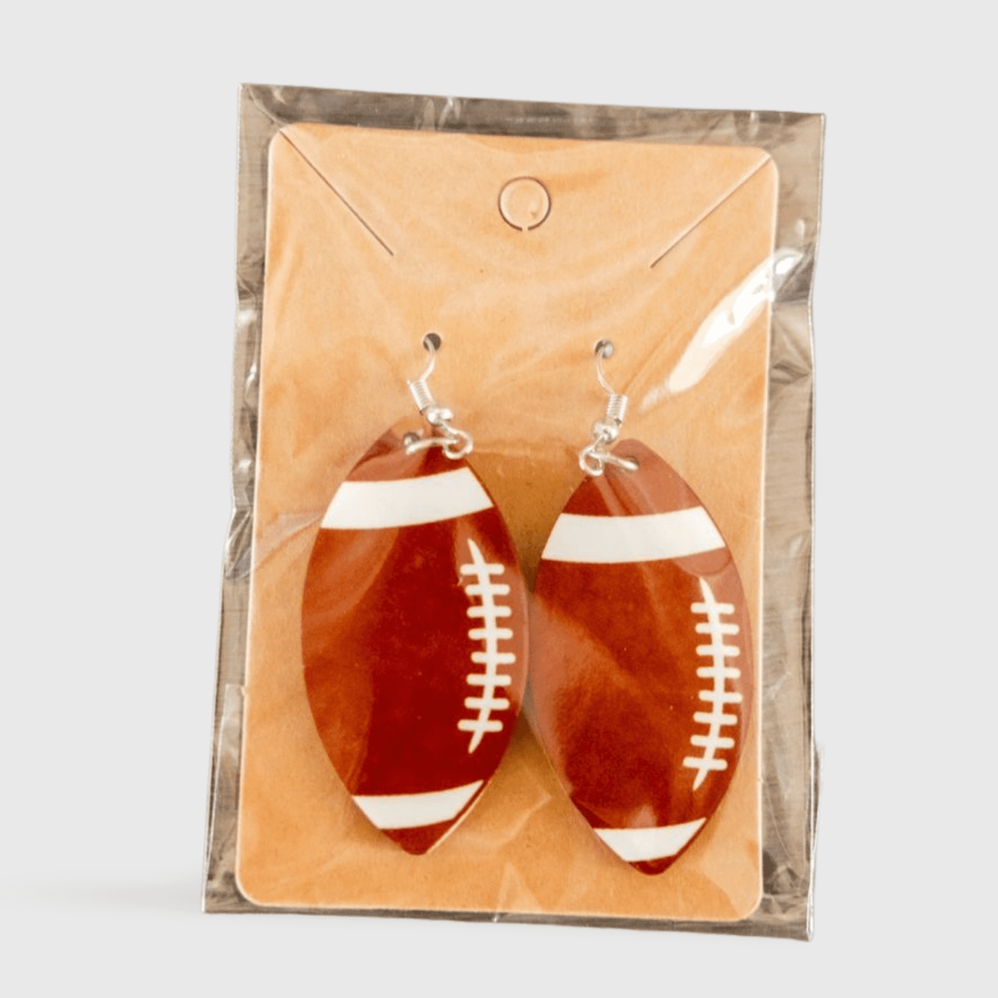 A pair of football earrings hanging on a card.