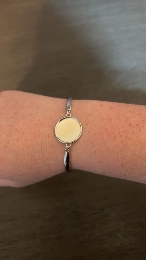 A person wearing a bracelet with a yellow circle on it.