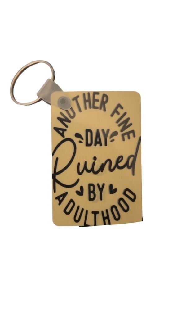 A key chain that says another fine day ruined by adulthood.